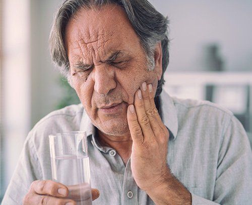 middle aged man holding his cheek in pain