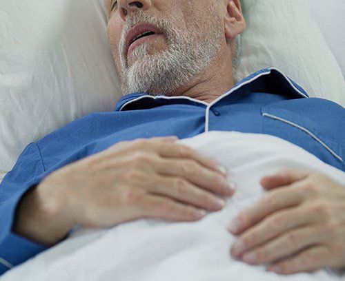 An elderly man sleeping  representing Sleep Apnea.