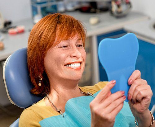 Elderly woman in dental chair smiling after dental fillings