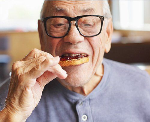 Elderly man eating toast with jelly
