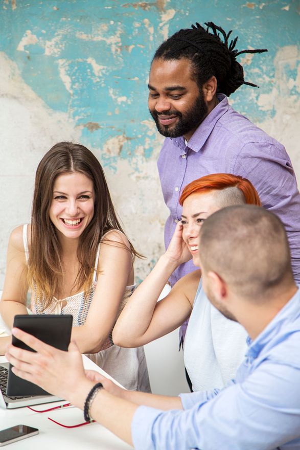 Een groep mensen zit rond een tafel en kijkt naar een tablet.