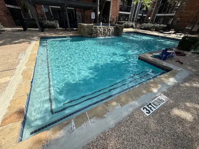 A rectangular swimming pool with a stone edge and steps. The water is turquoise. Sign indicates 3ft depth.