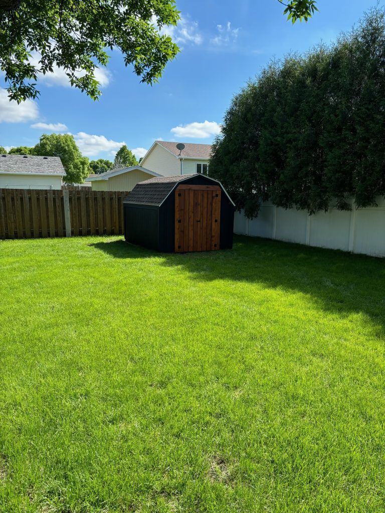 A shed is sitting in the middle of a lush green yard.