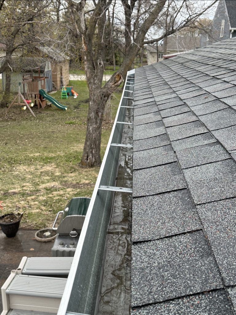 A gutter on the side of a roof with a playground in the background.
