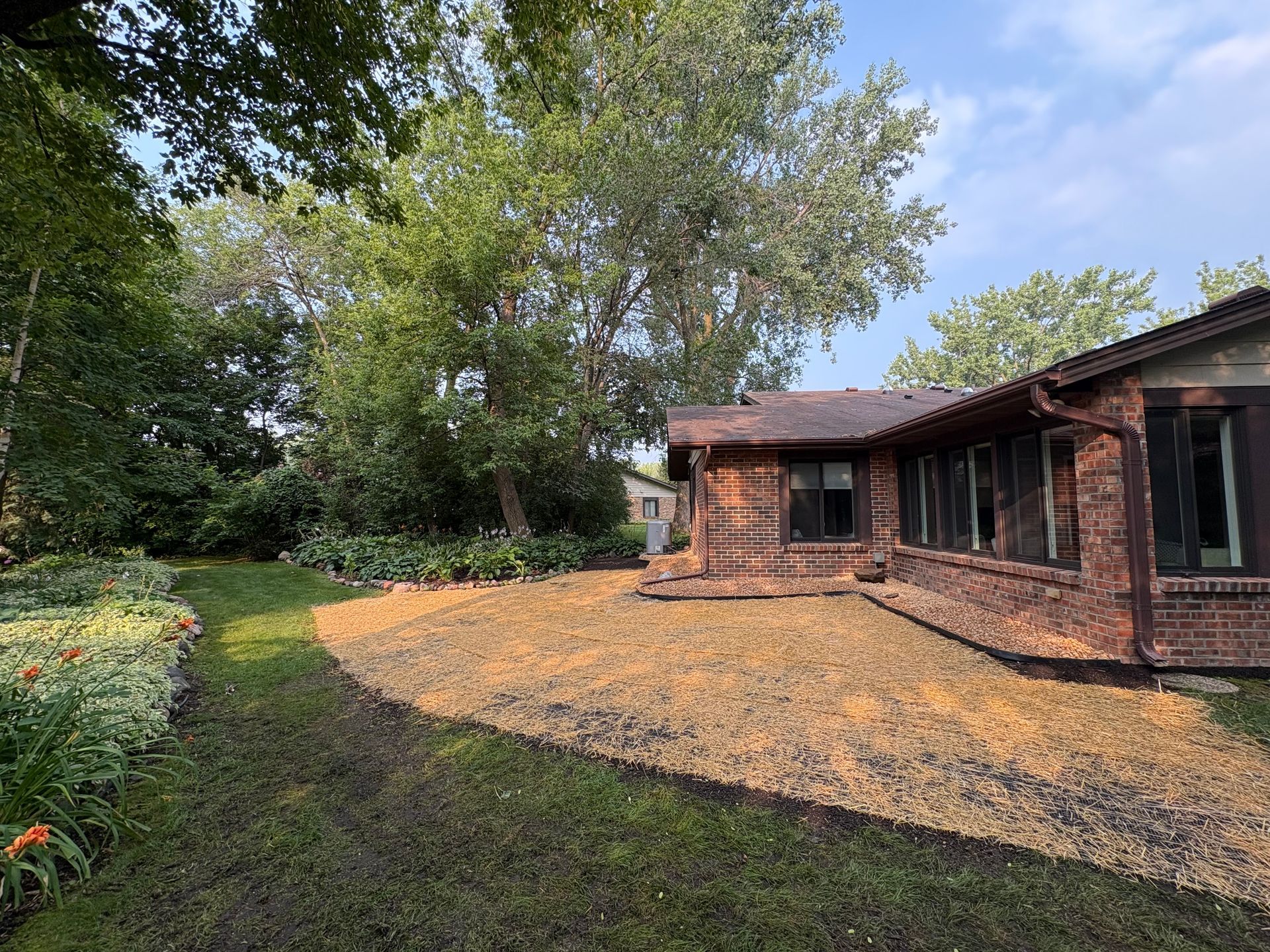 A stone walkway in a garden surrounded by plants and trees.