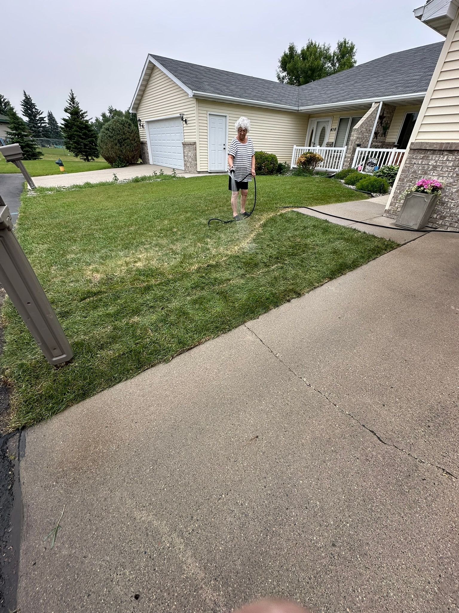 Woman standing on grass in front of a house, wearing a striped shirt.