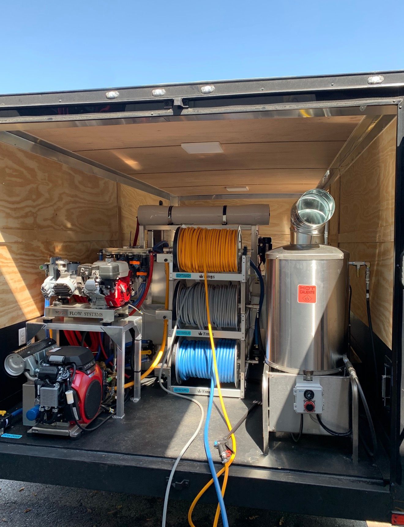 A person is using a high pressure washer to clean a wooden deck.