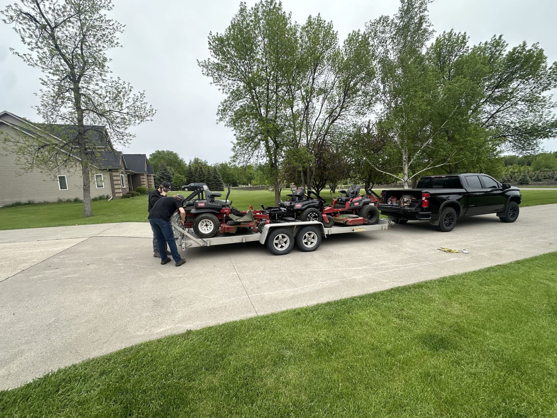 A truck is towing a trailer with four atvs on it.