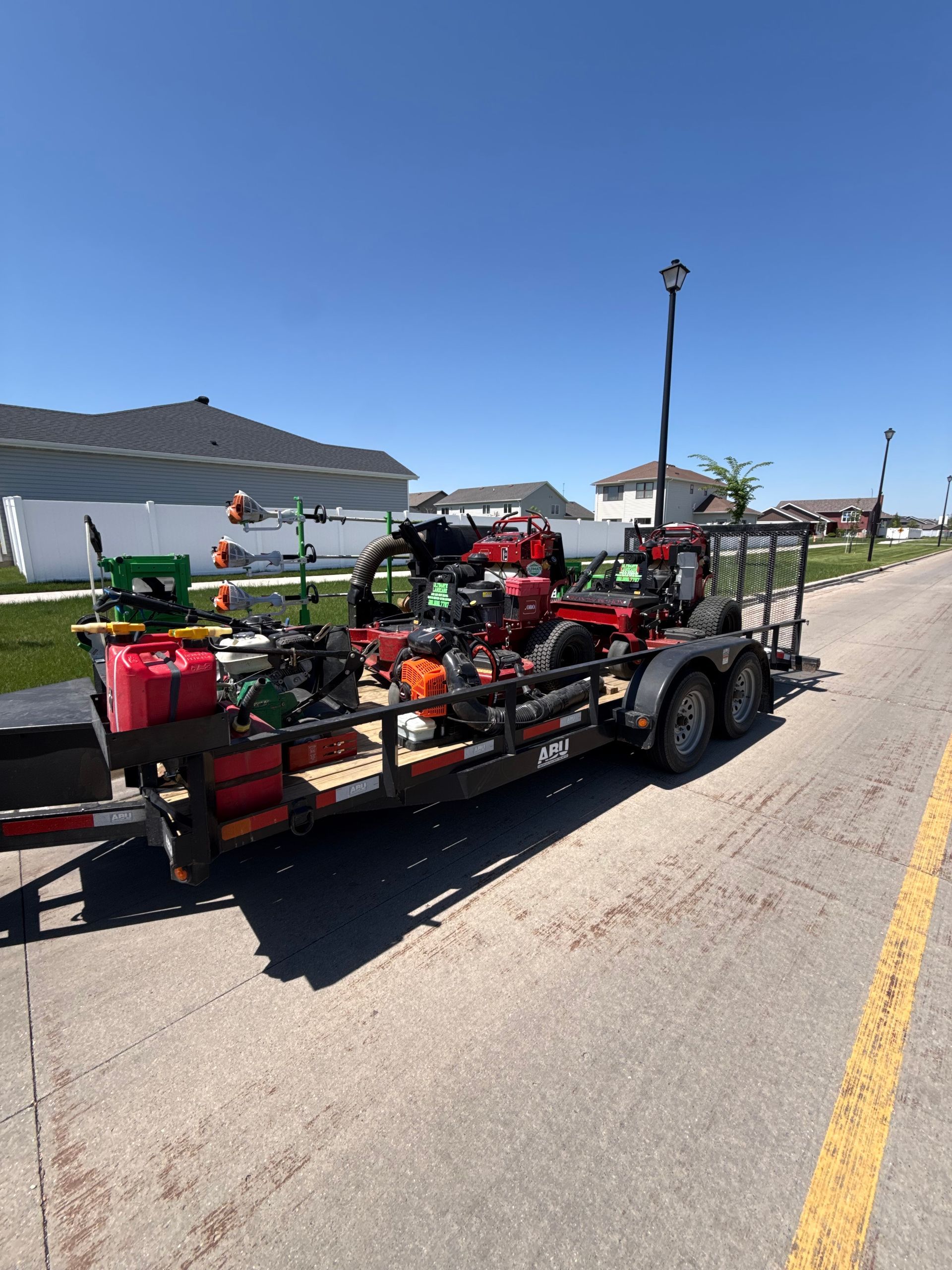 Trailer loaded with red equipment parked beside a road on a sunny day