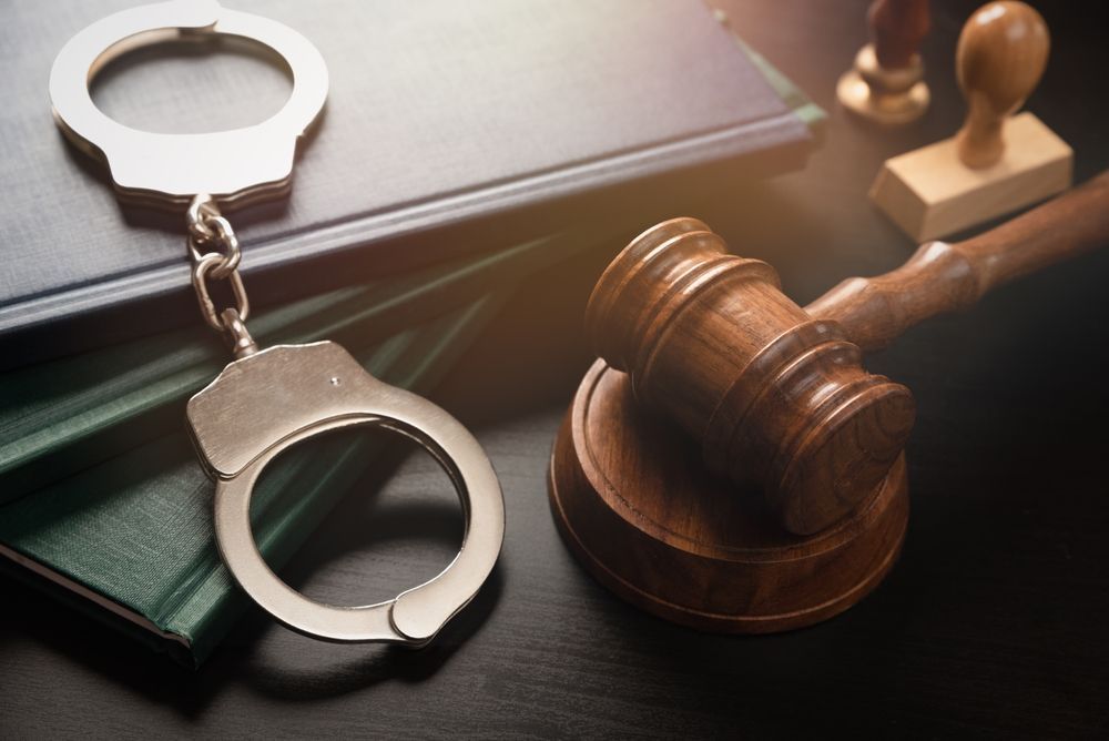 A pair of handcuffs sitting on top of a book next to a judge 's gavel.