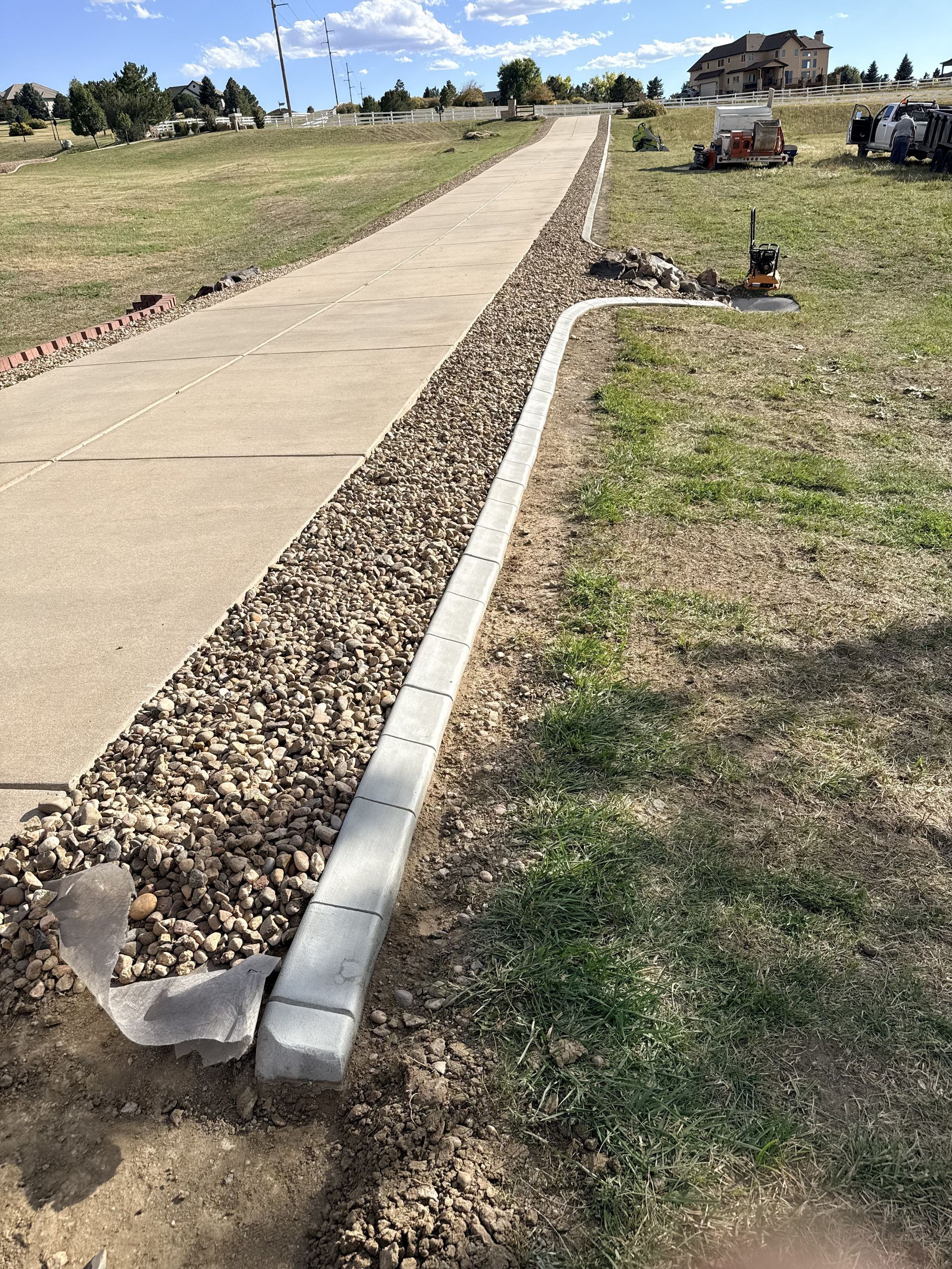Newly poured concrete curb alongside a sidewalk in a residential area.
