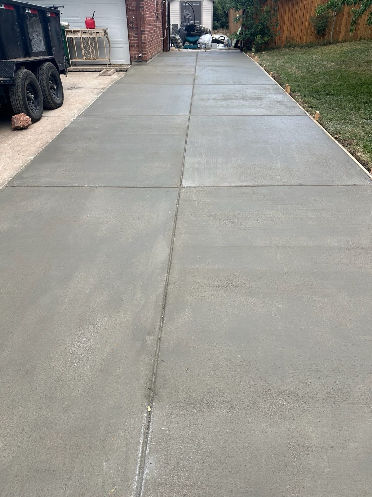 Newly poured concrete driveway, gray surface, with expansion joints.