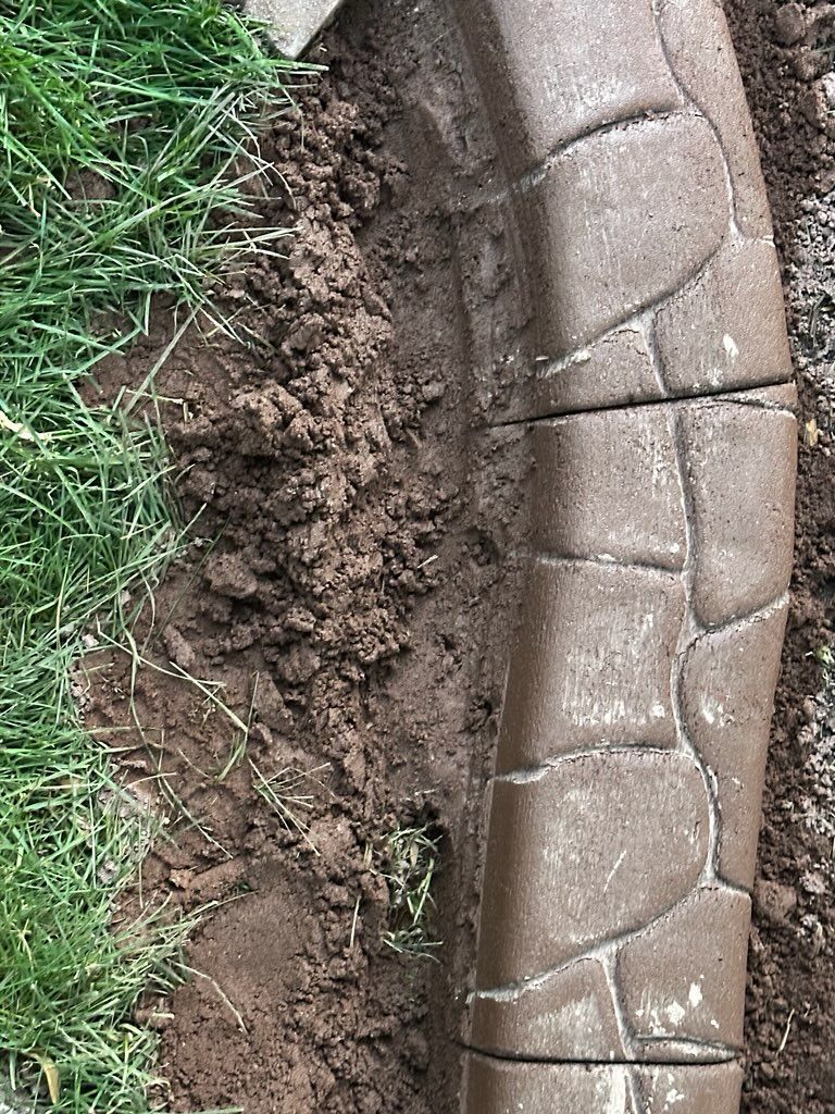 Brown concrete edging separating grass and soil.