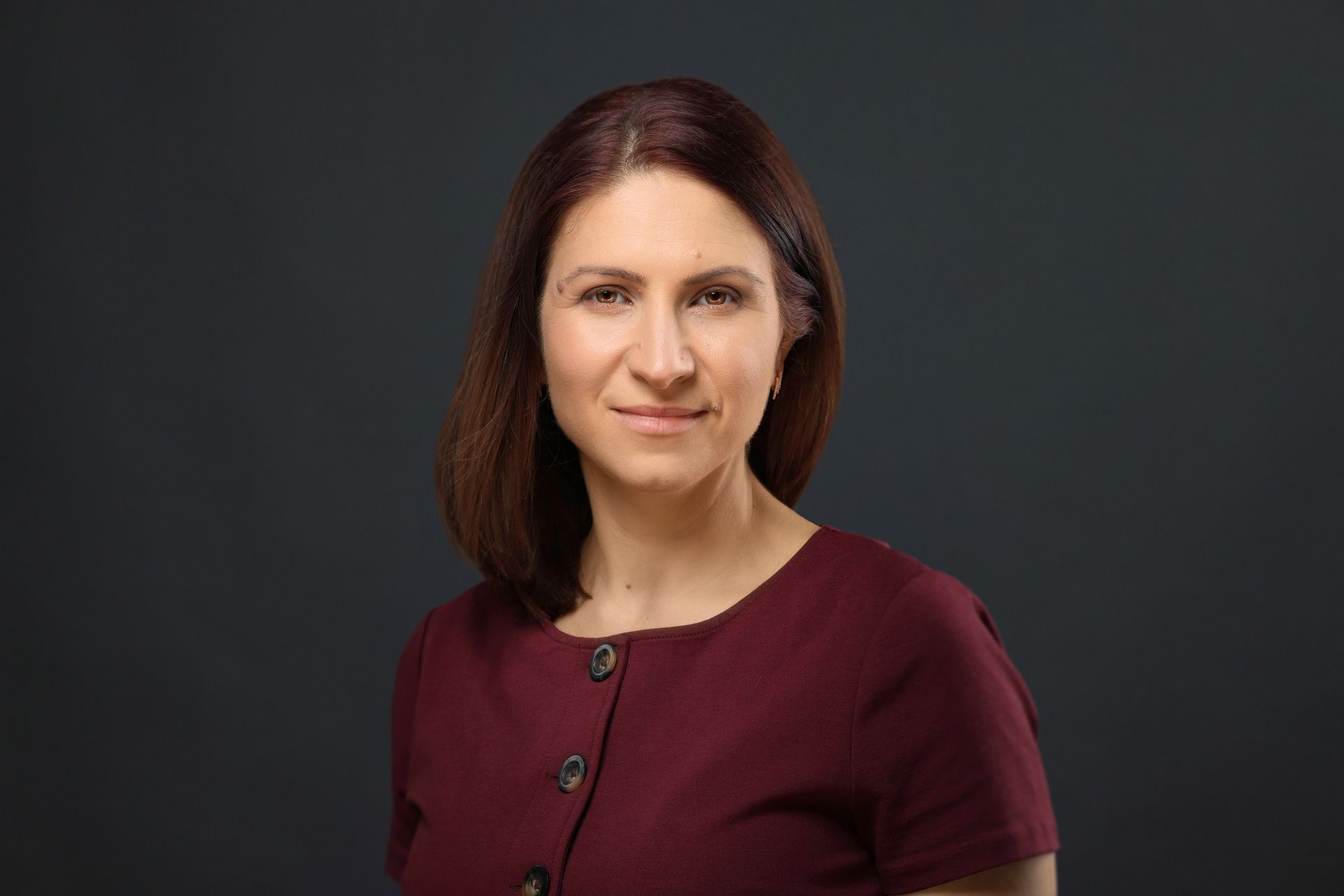 A woman in a maroon dress is smiling for the camera.