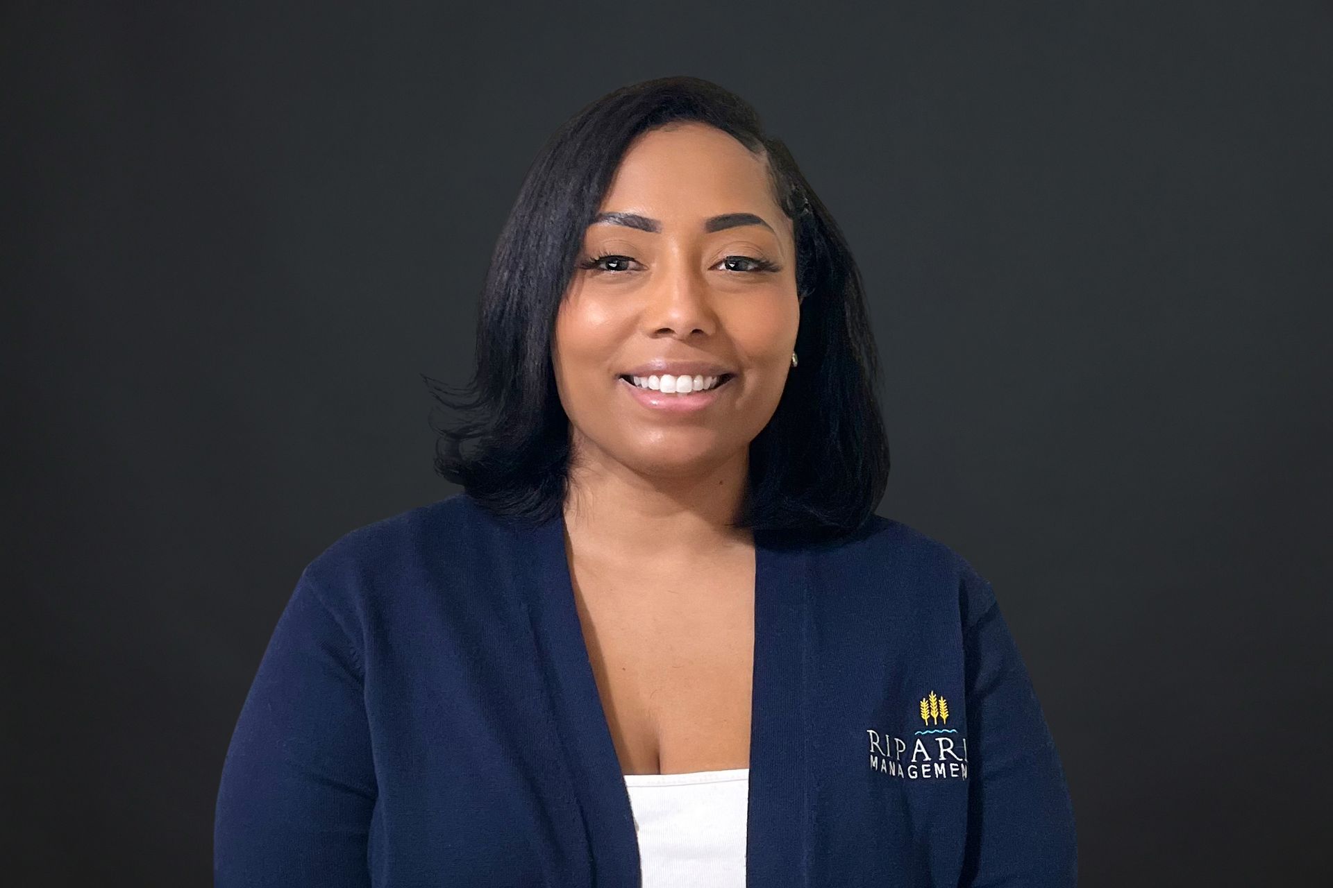 A woman is wearing a blue sweater and smiling for the camera.