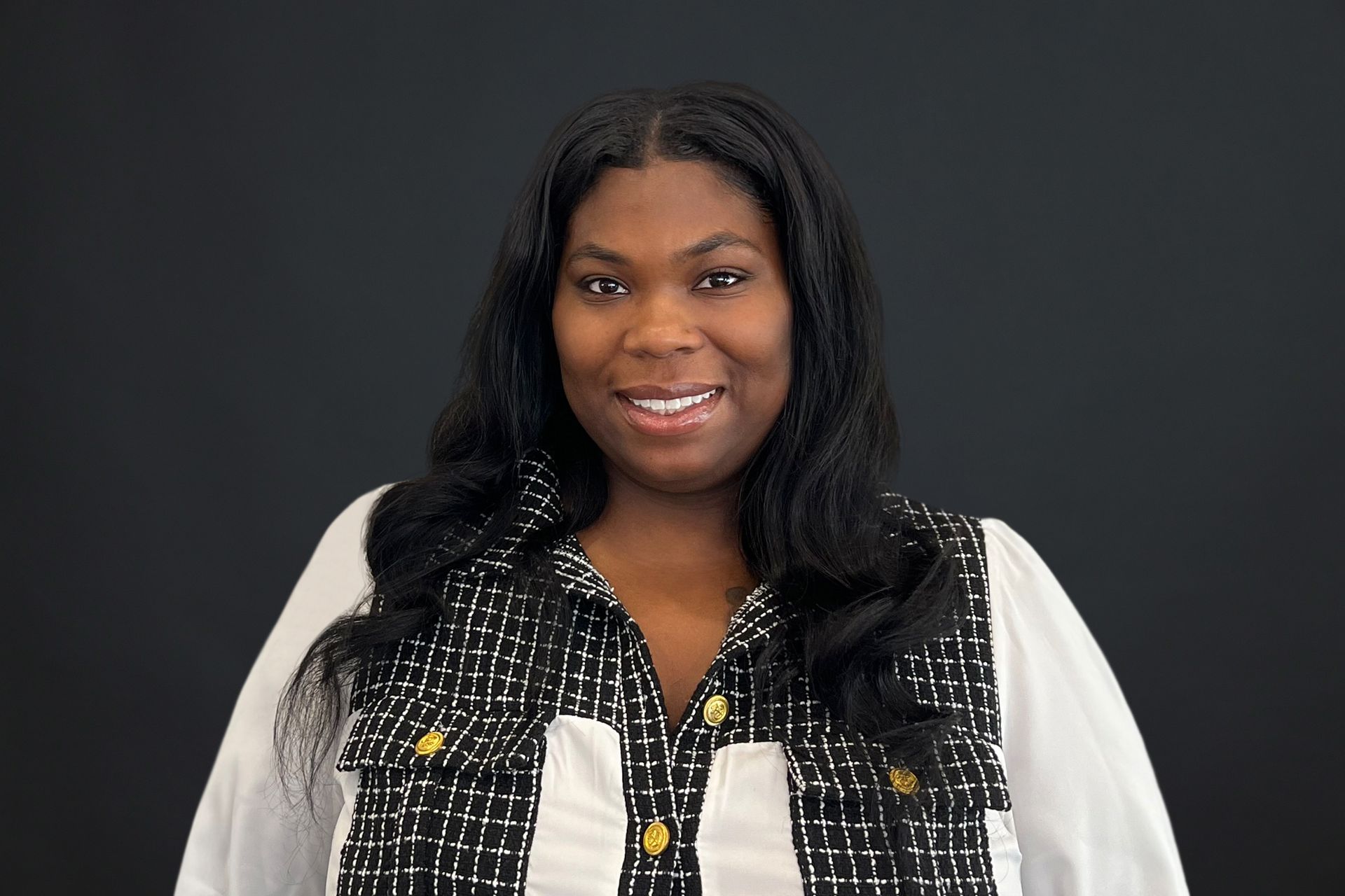 A woman in a black and white jacket is smiling for the camera.