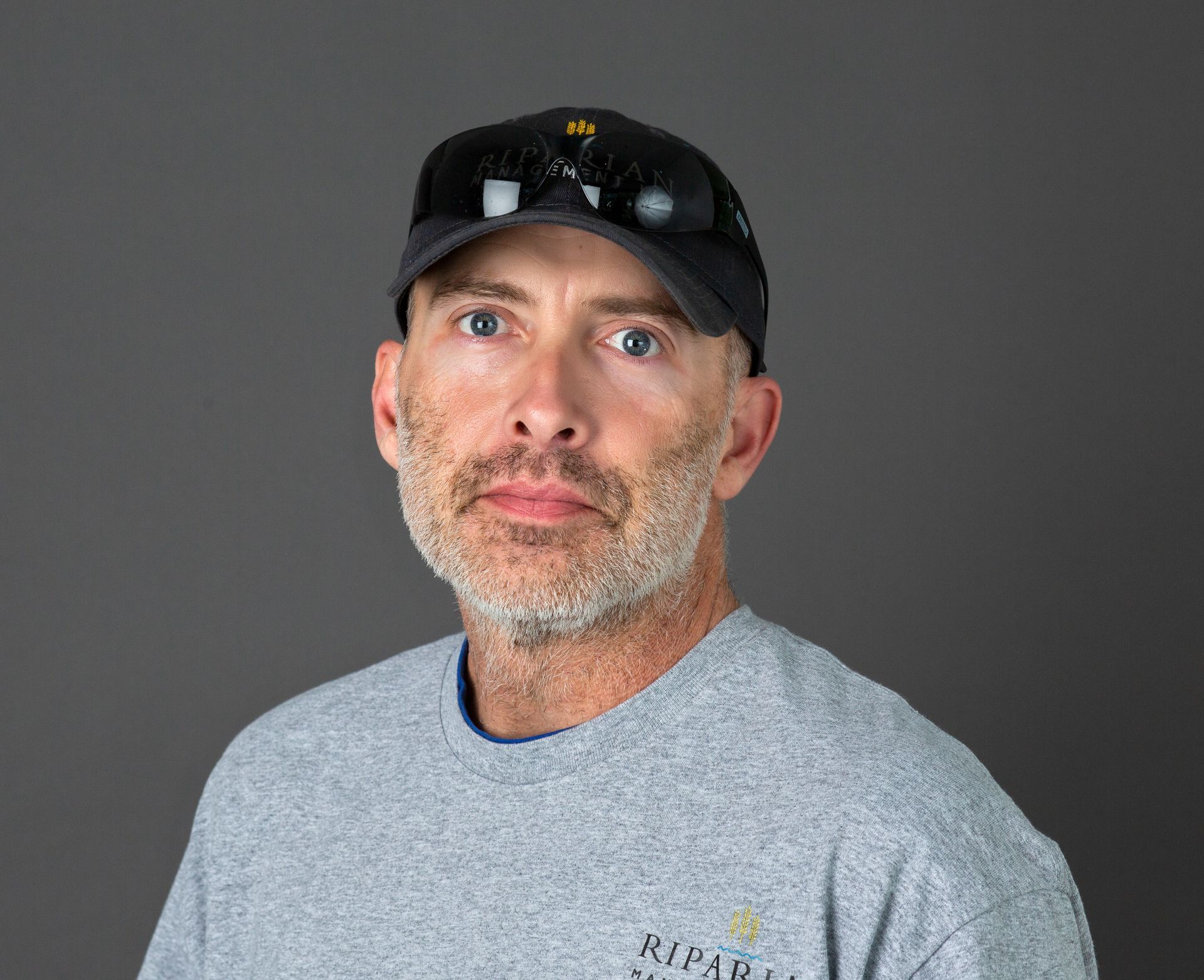 A man wearing a hat and sunglasses is looking at the camera.