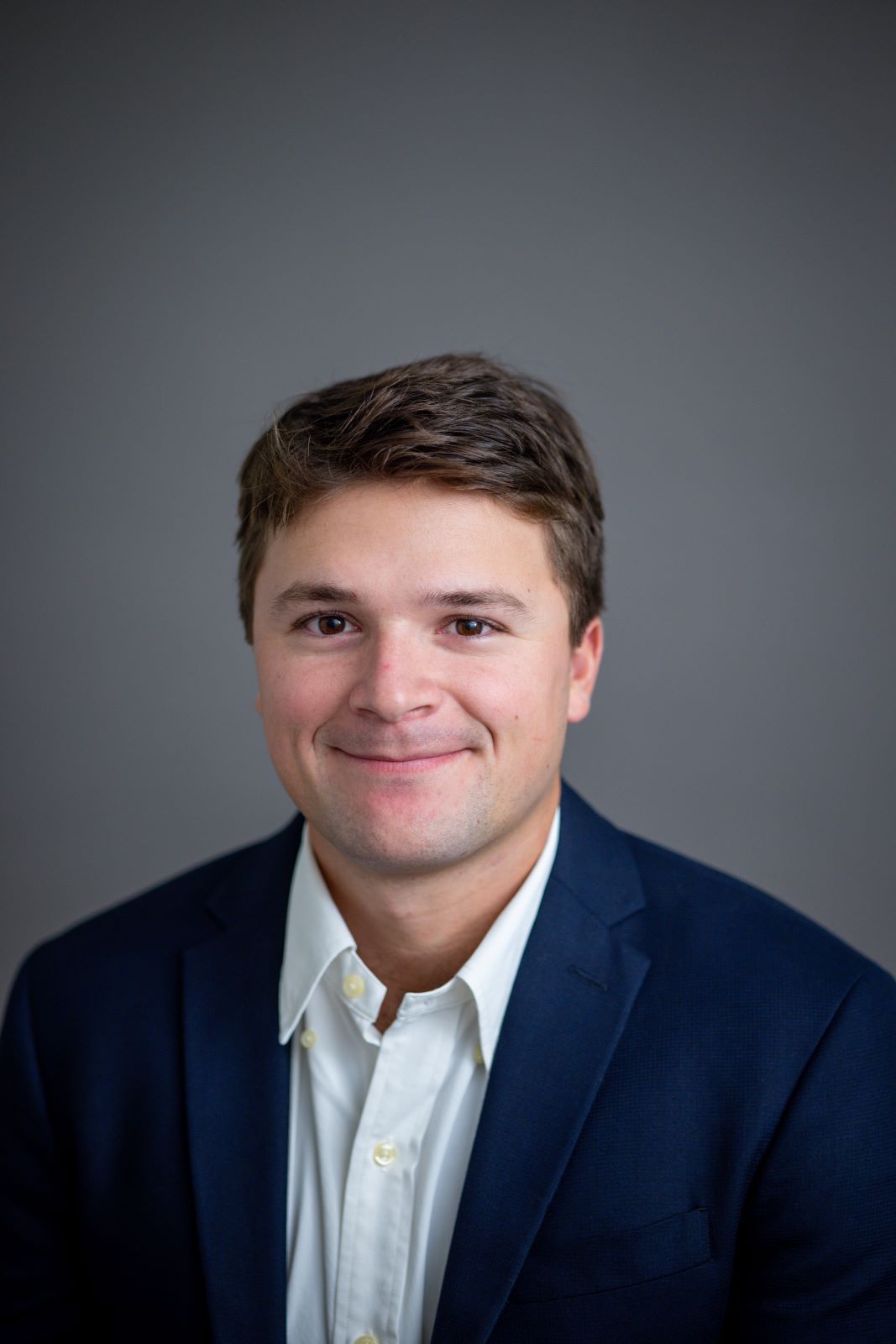 A man in a suit and white shirt is smiling for the camera.