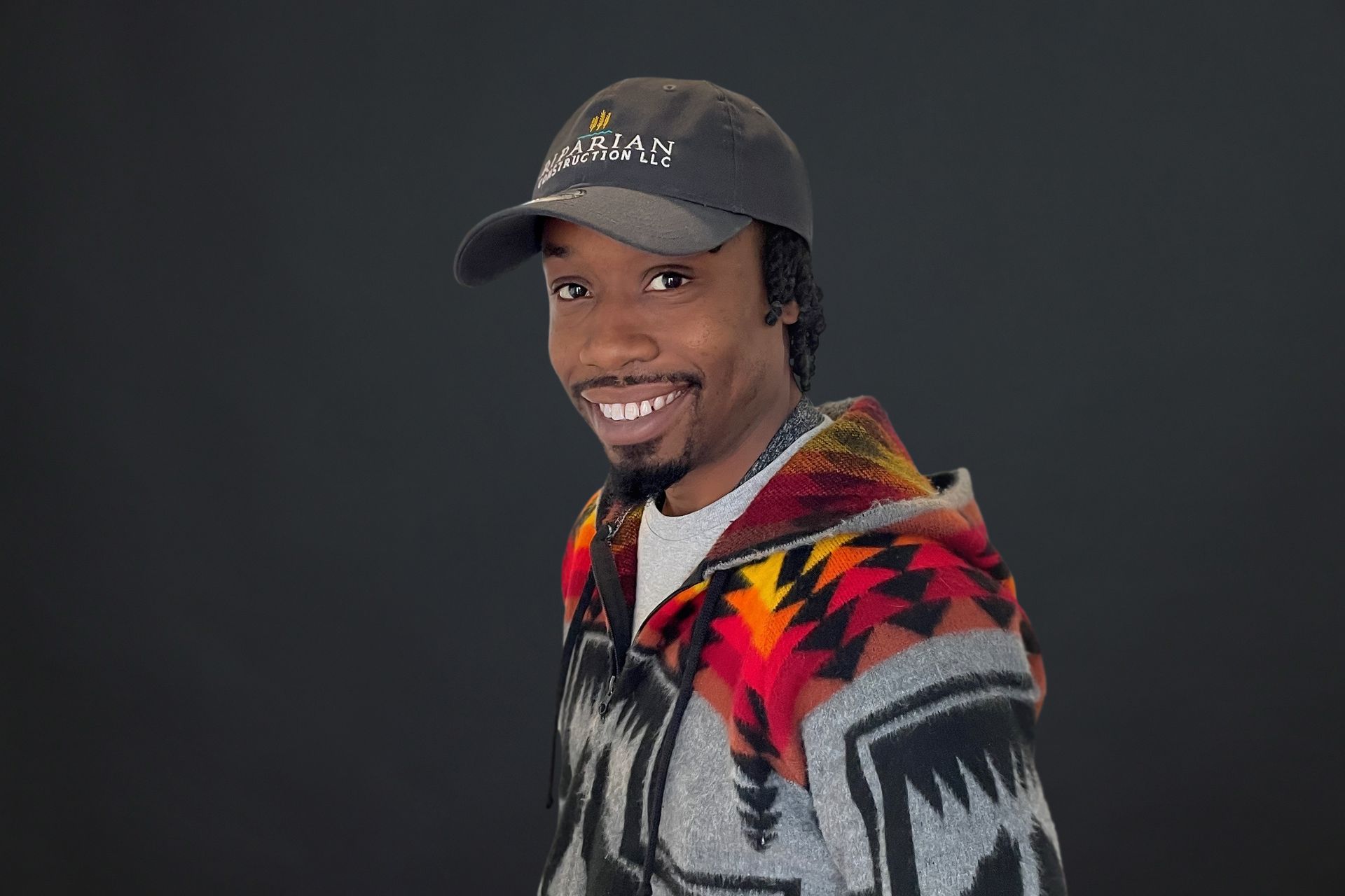 A man wearing a hat and a sweater is smiling.