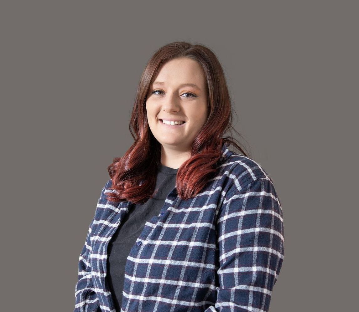 A woman in a plaid shirt is smiling for the camera.