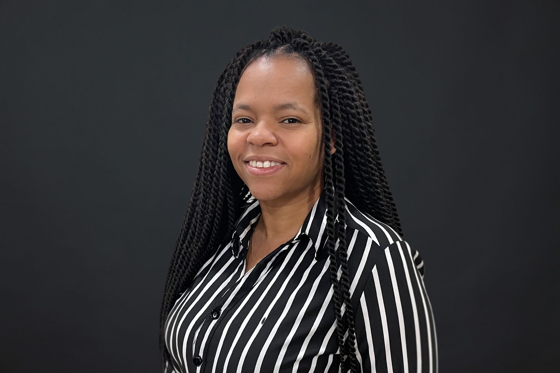 A woman with braids is wearing a black and white striped shirt.