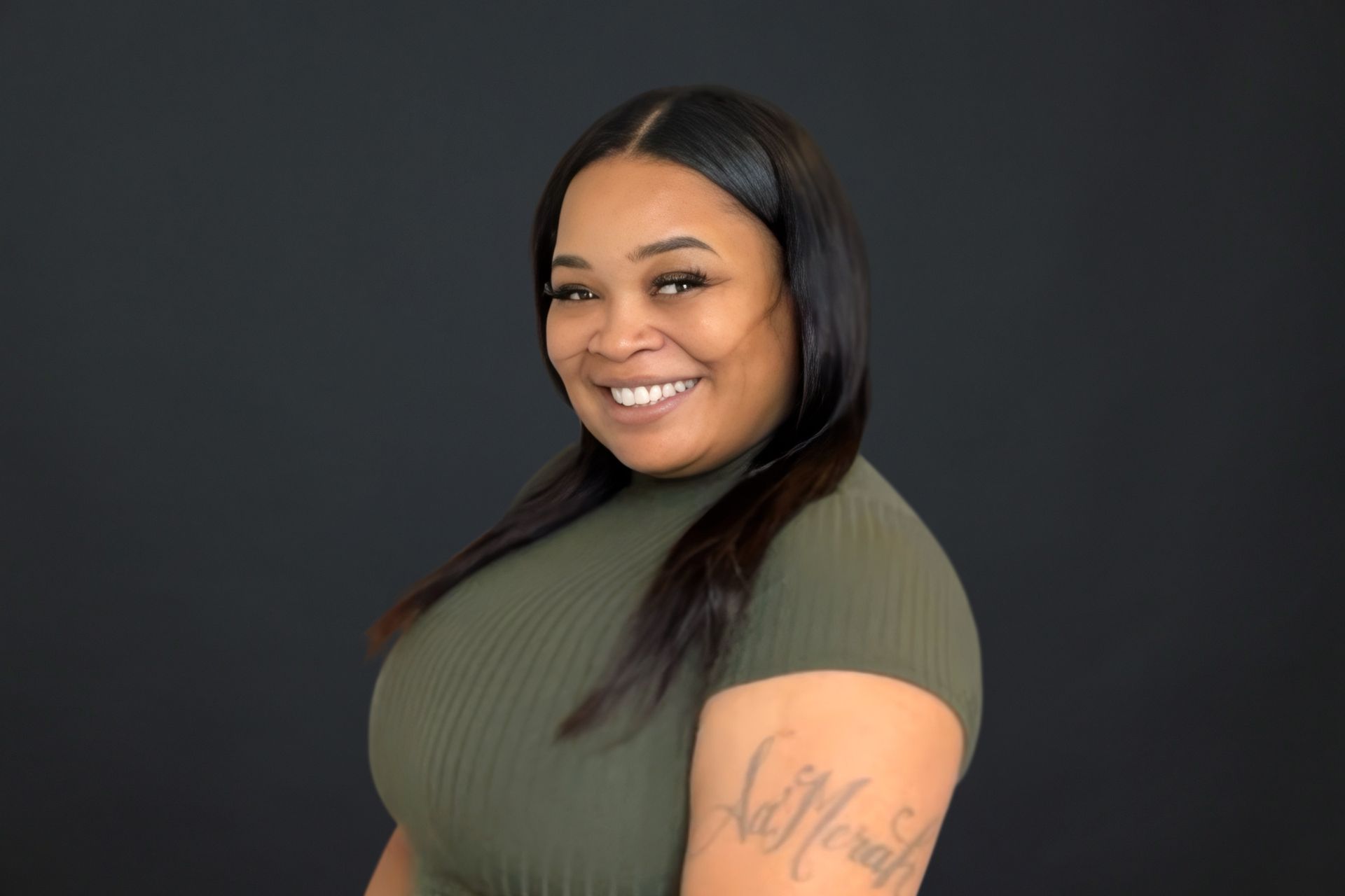 A woman with a tattoo on her arm is smiling for the camera.