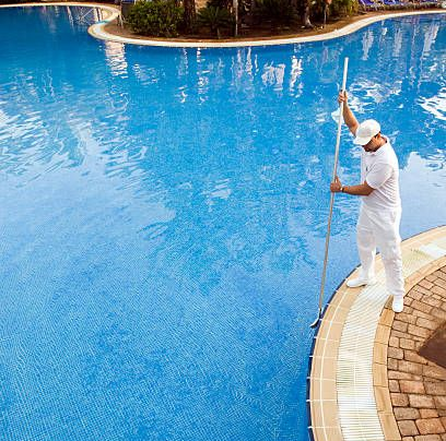 Pool maintenance worker brushing walls