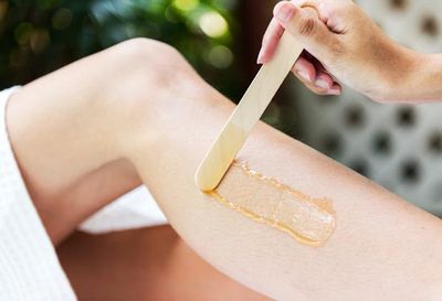 Leg Waxing — Woman Applying Wax on Her Legs in Beverly Hills, CA