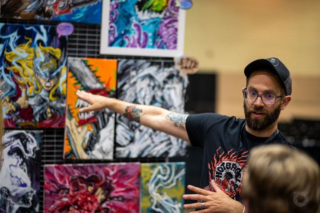 Artist showing his work off to exhibitors walking past at the 2022 Capital City Comic Con event