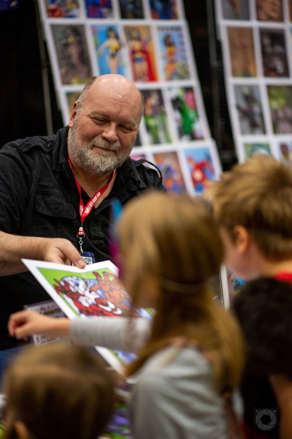 A 2022 Capital City Comic Con event volunteer handing out prints to kids