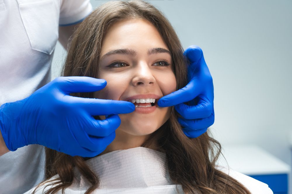 Woman In Dental Chair, Teeth Examined By Gloved Hands— New Leaf Dentists In Erina, NSW