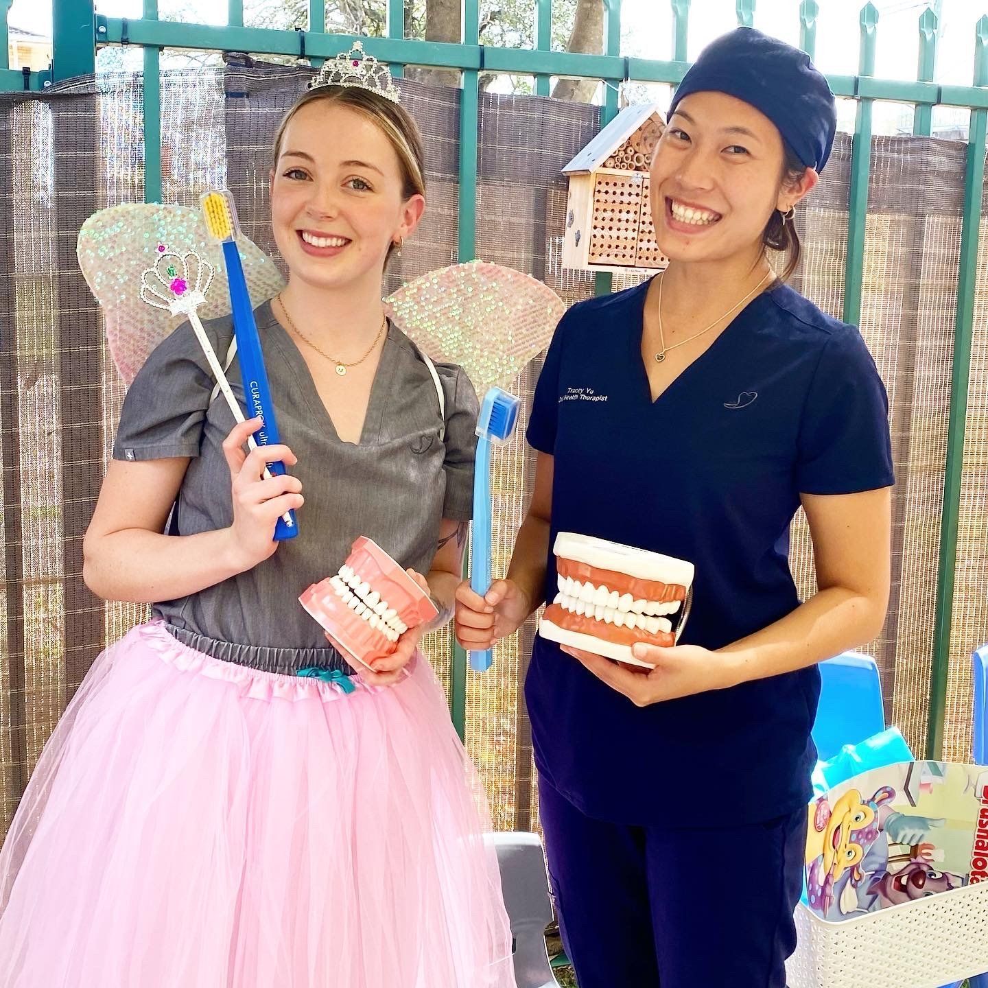 Two Women Are Holding Toothbrushes and Teeth Models — New Leaf Dentists in Erina, NSW