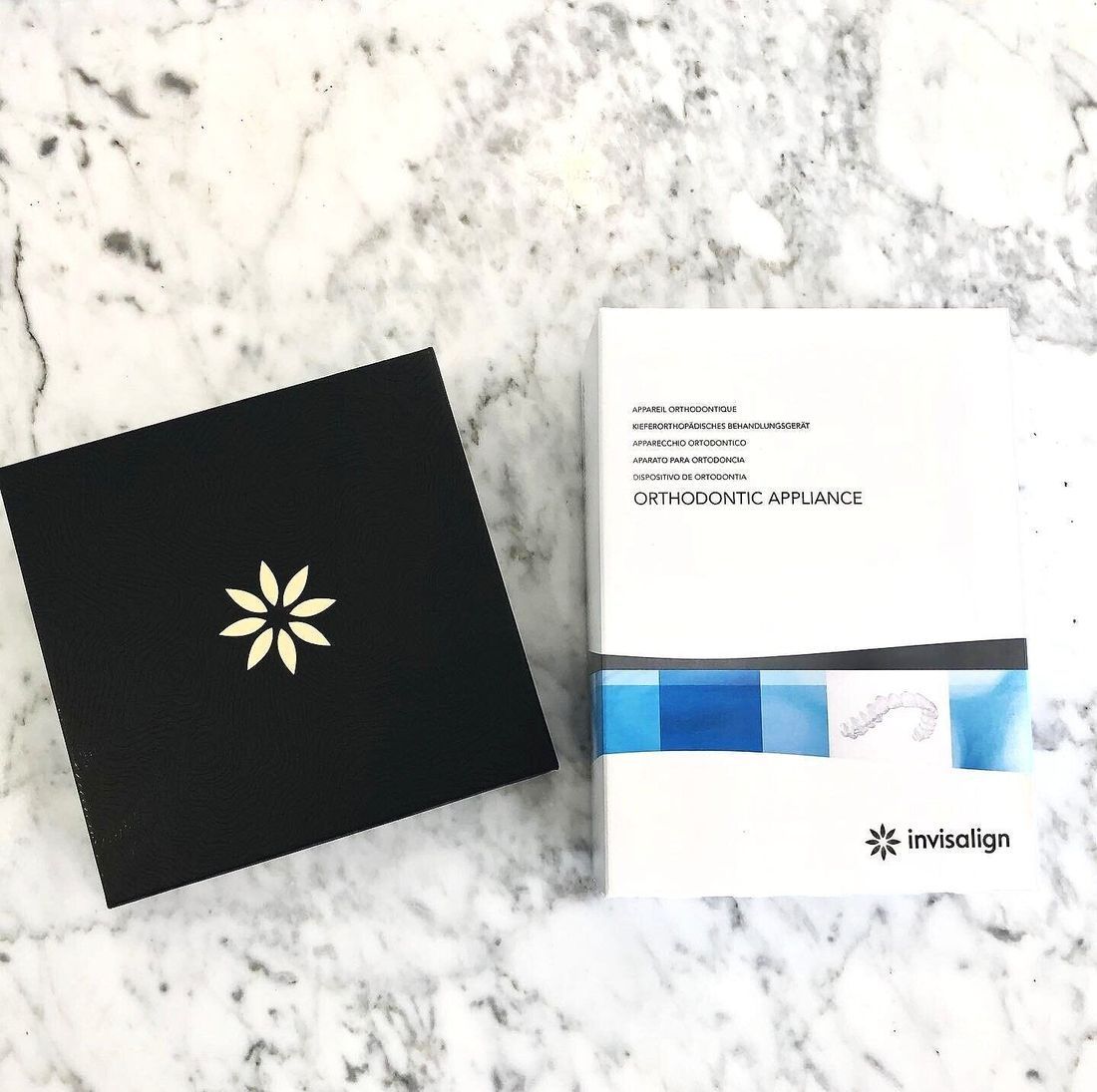 A Box of Invisalign is Sitting on a Marble Surface Next to a Black Box — New Leaf Dentists in Erina, NSW