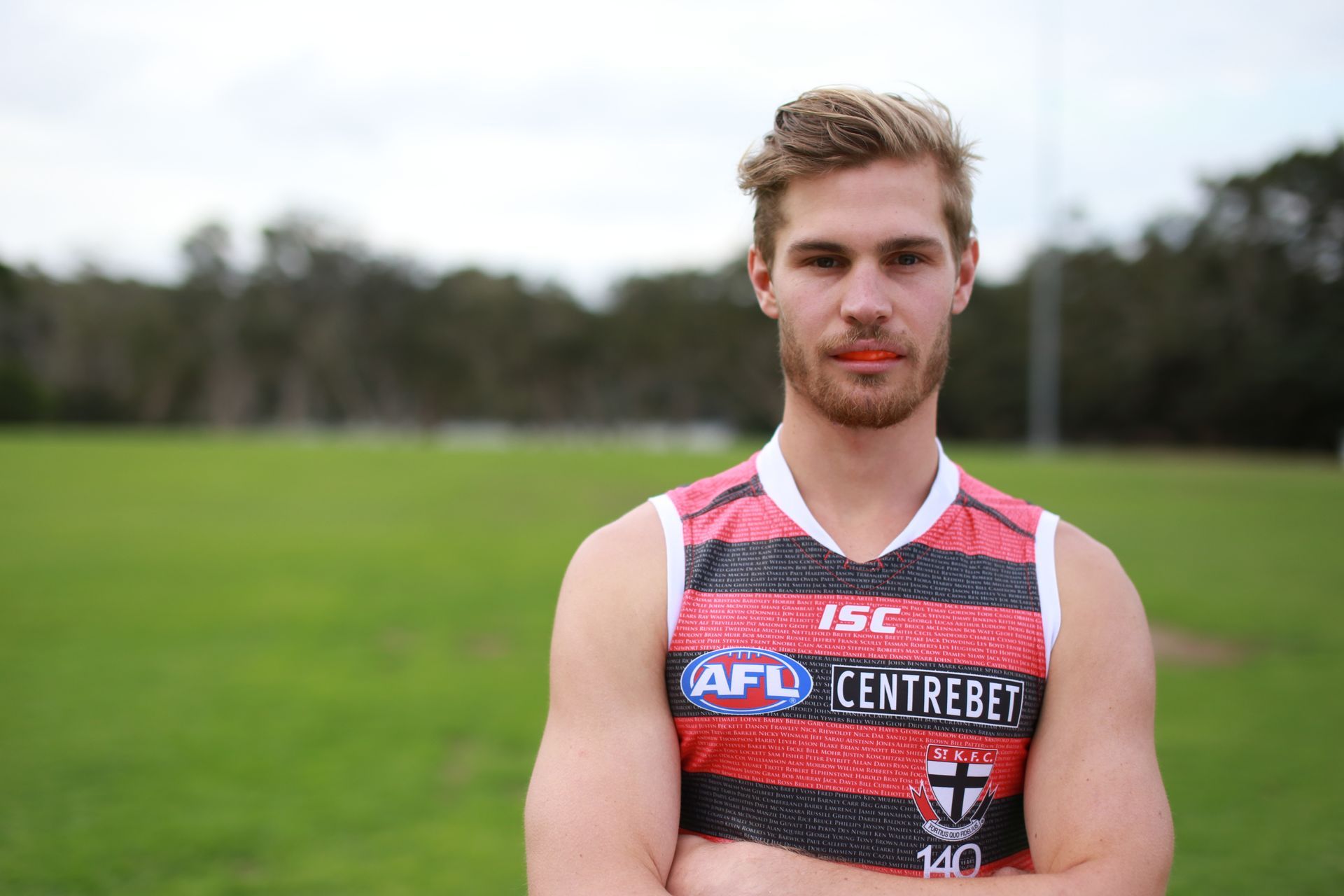 Man in a Sports Jersey Stands on a Green Field — New Leaf Dentists In Erina, NSW