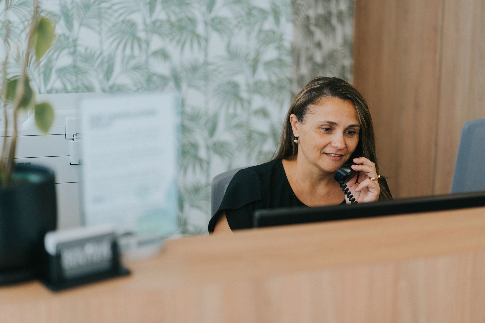 Woman at a Reception Desk Talking on the Phone — New Leaf Dentists In Erina, NSW