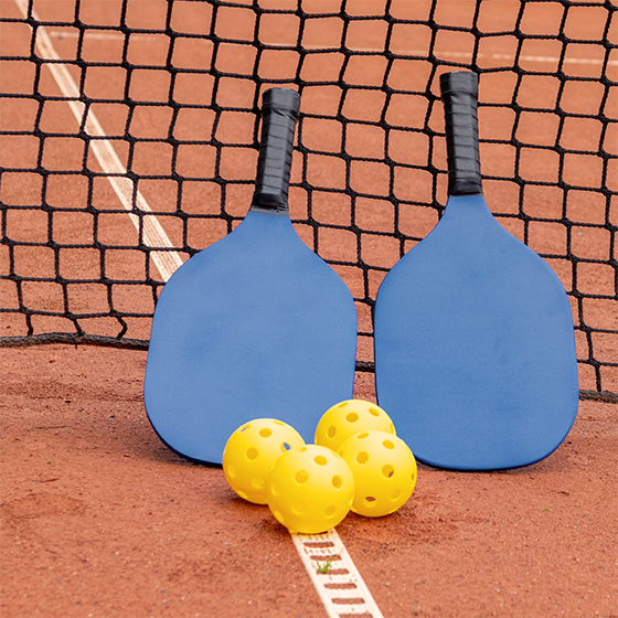 Two blue rackets and three yellow balls on a tennis court