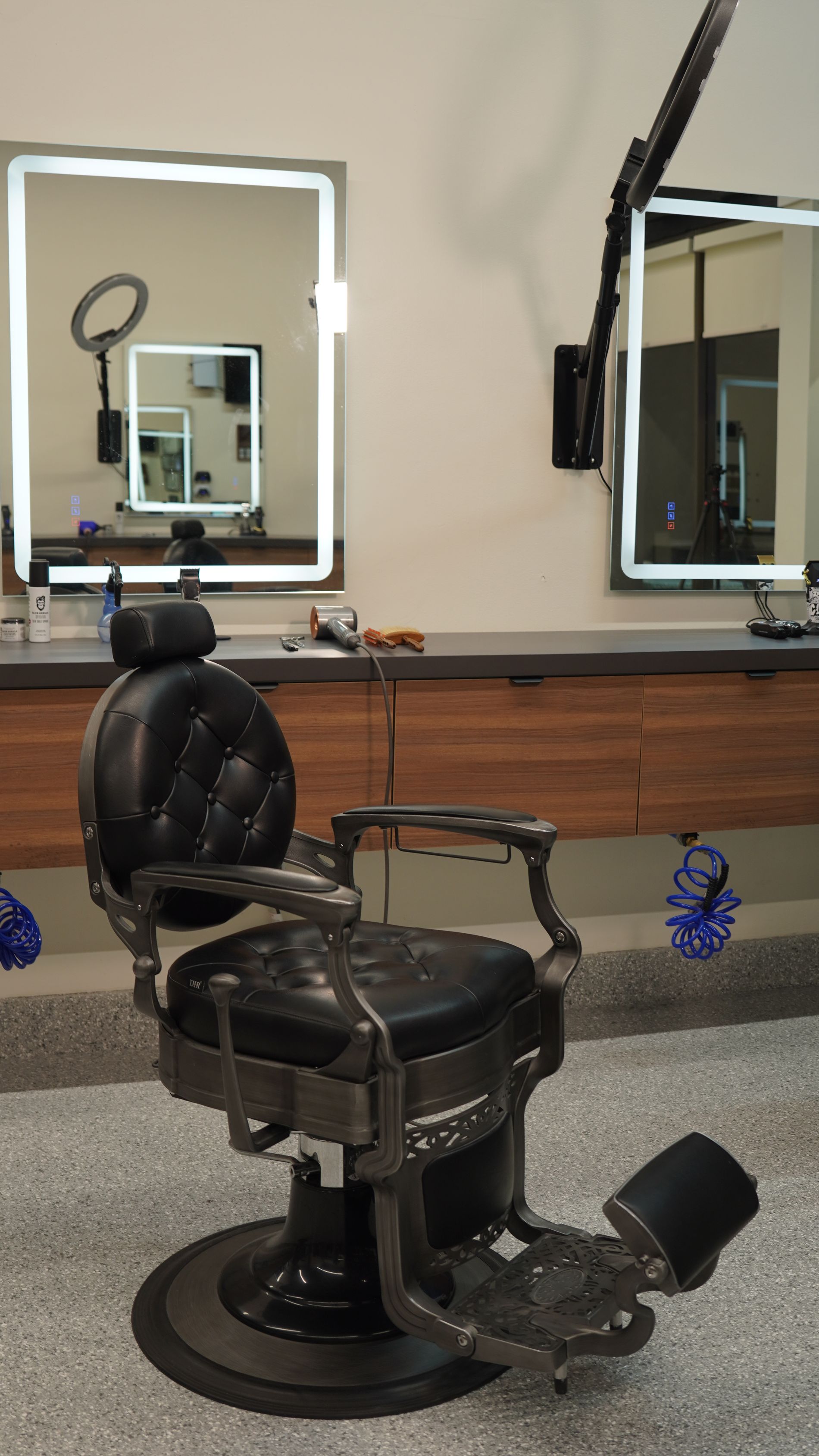 Vintage black barber chair in a salon with backlit mirrors.