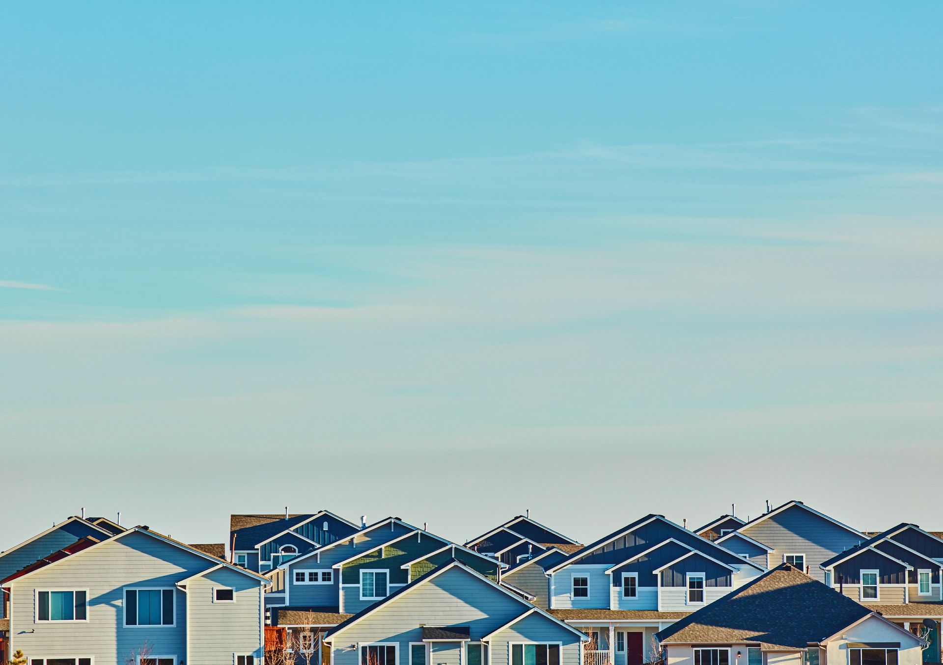Row of houses with blue-gray exteriors and dark roofs under a clear, light blue sky.