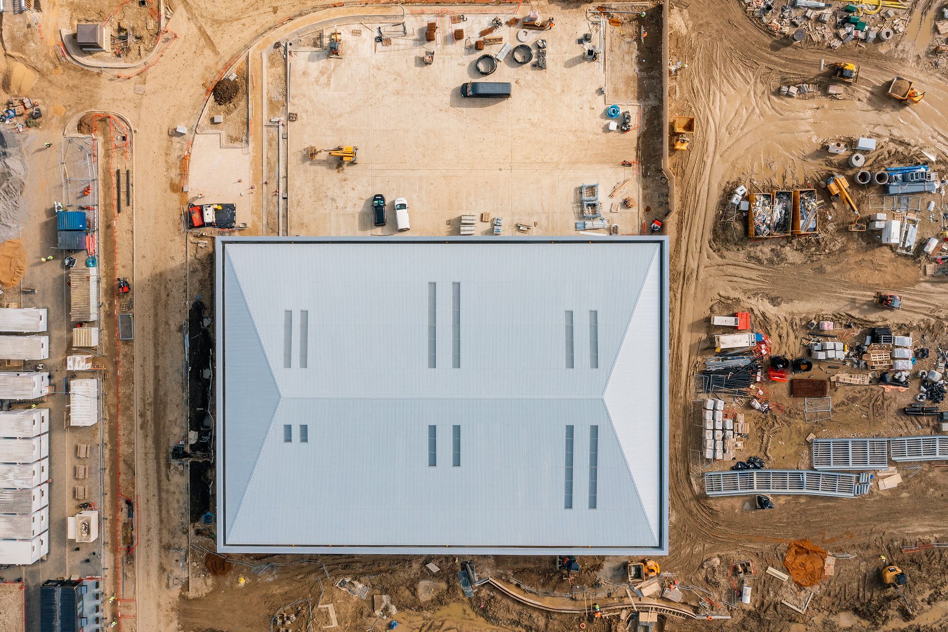 Aerial view of a large building under construction with construction equipment surrounding it. Aerial view of a large building under construction with construction equipment surrounding it.
