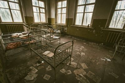 A room with a lot of beds in it and a lot of papers on the floor.