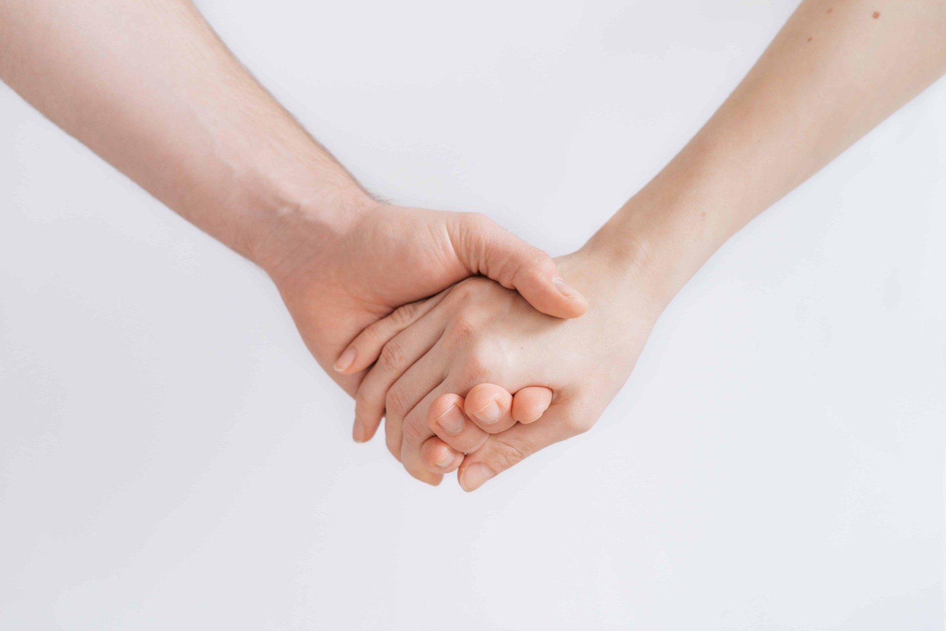 A man and a woman are holding hands on a white background.