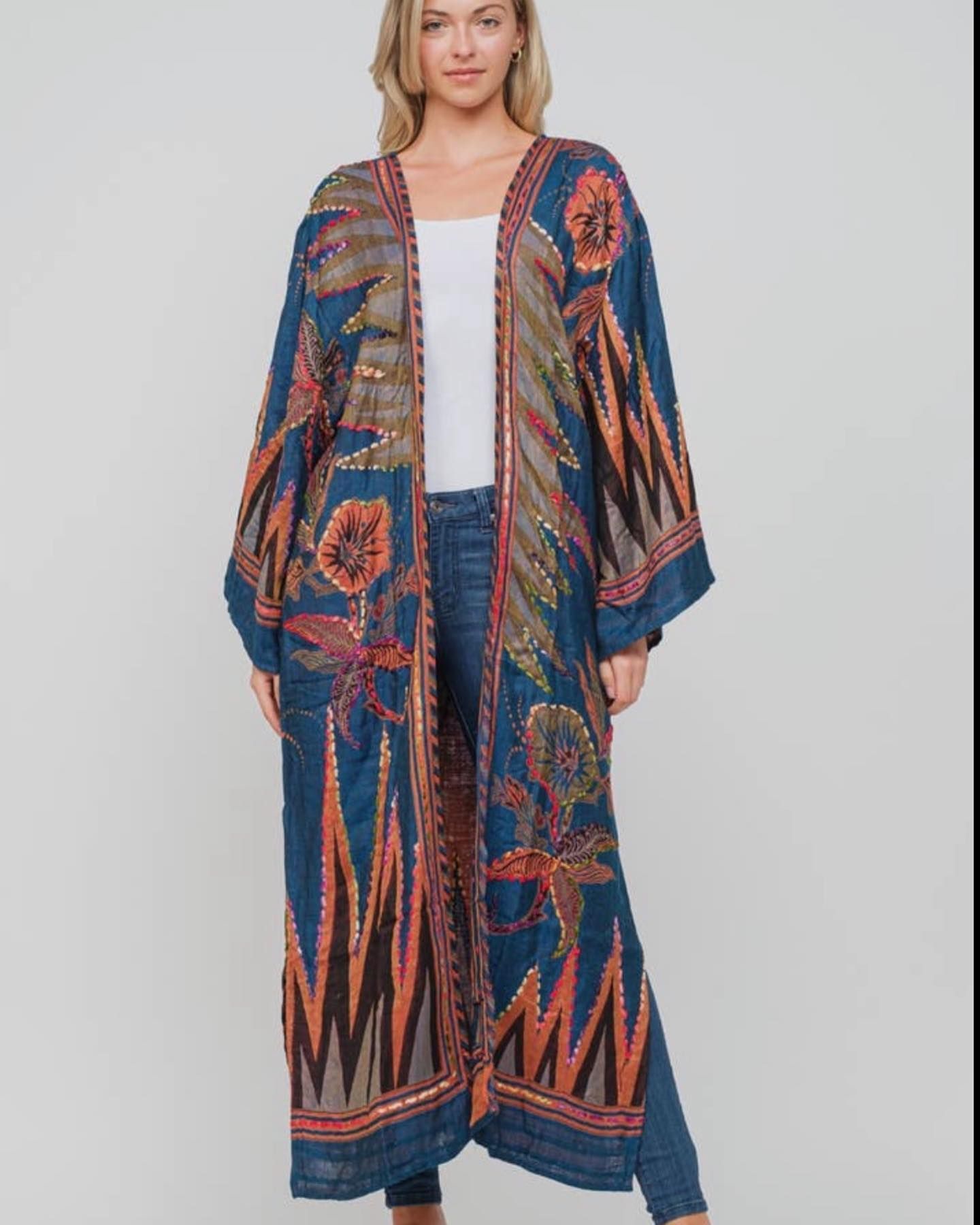 Woman wearing a long, open blue floral kimono over a white top and jeans.