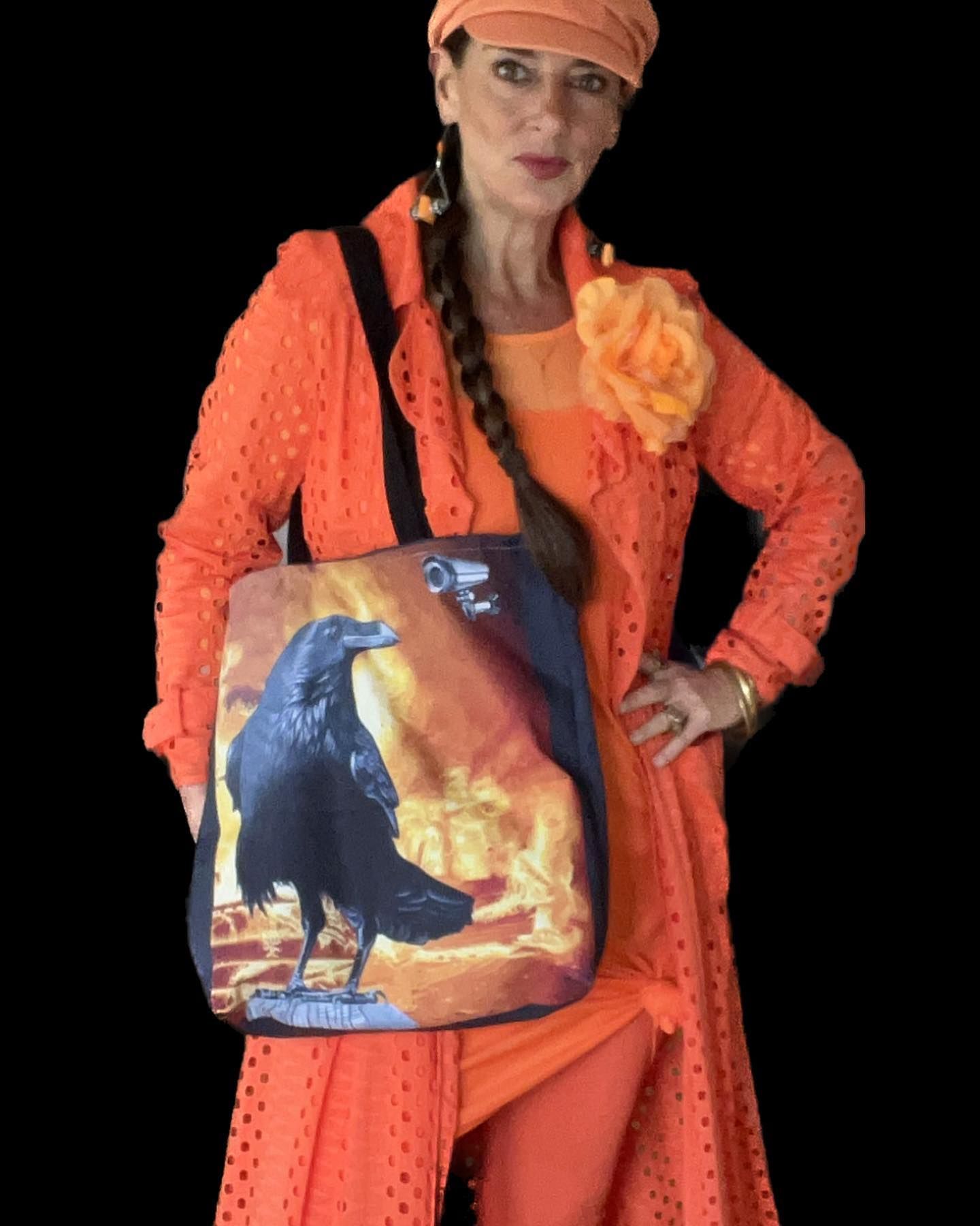 Woman in orange outfit with raven tote bag against a black background.