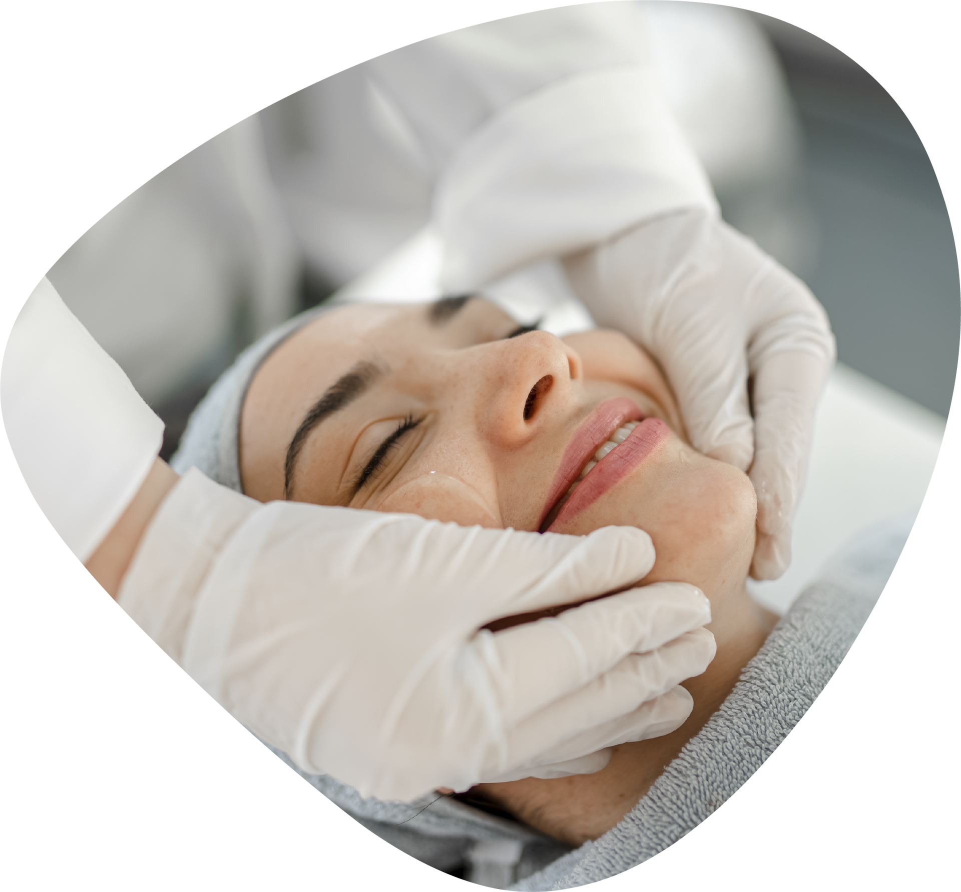 A woman is getting a facial treatment with gloves on her hands.