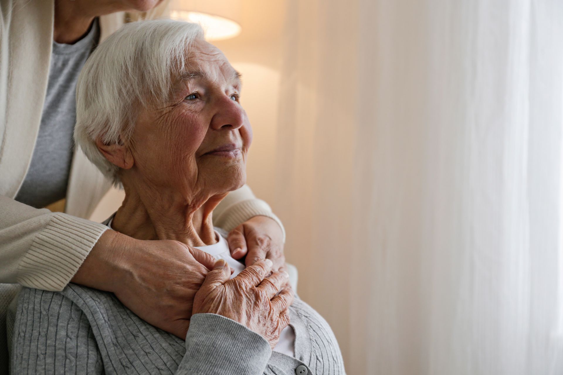 A caregiver places her hands on the shoulders of a person with dementia to offer comfort.
