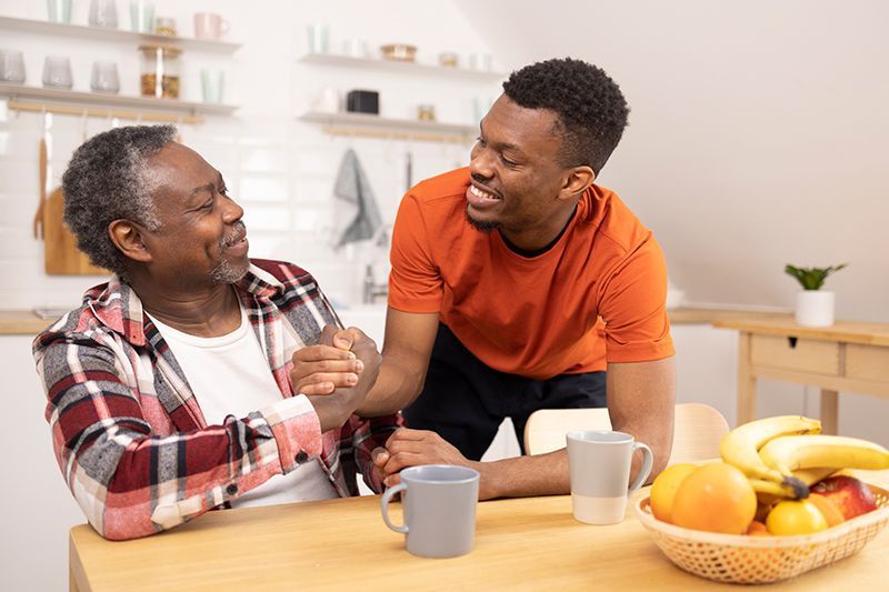 A vibrant older adult laughing with his son captures the essence of living fully with chronic illnes