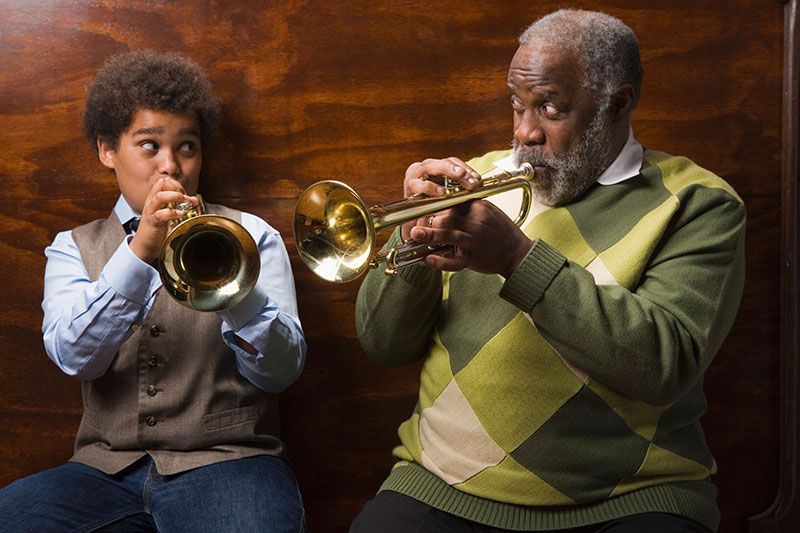 An older man plays a trumpet with his grandson, knowing it can help improve cognitive health for sen