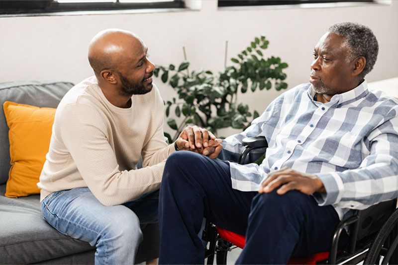 A man who knows how to address aggression in someone with memory loss holds his father’s hand.