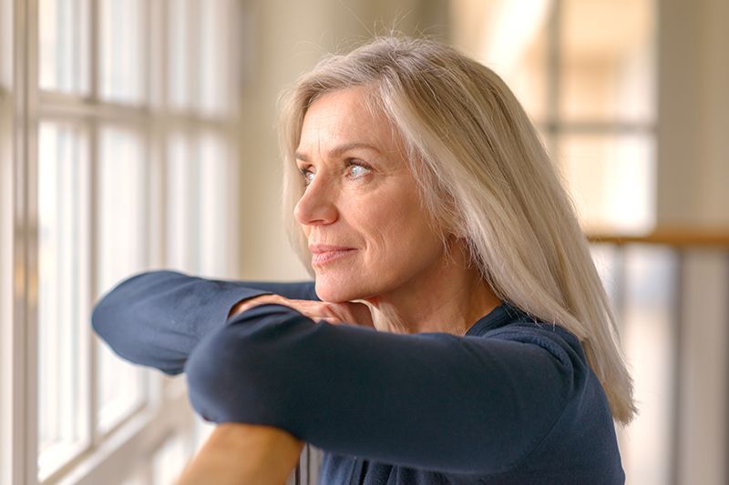 A woman who understands the best way to deal with intense emotions in dementia care gazes out the window.