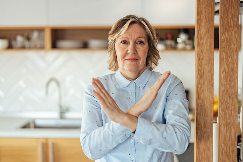 A woman who had been constantly saying yes as a caregiver crosses her arms in an X shape to indicate